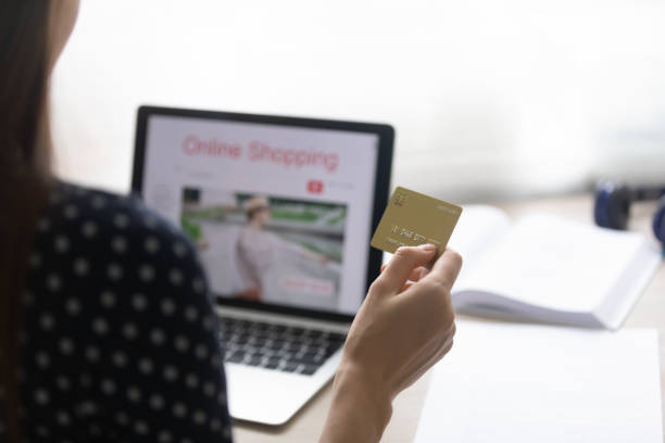 istock Young woman sitting by pc screen holding card in hand 1303320197