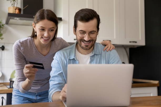 istock Happy young spouses paying online by card via e-banking app 1303320834