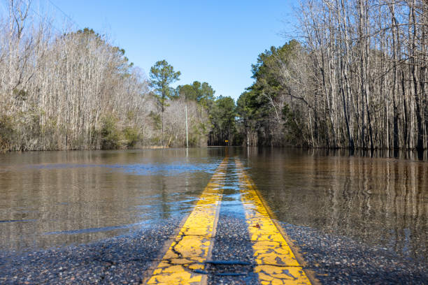 River flooding submerges road after heavy rains stock photo