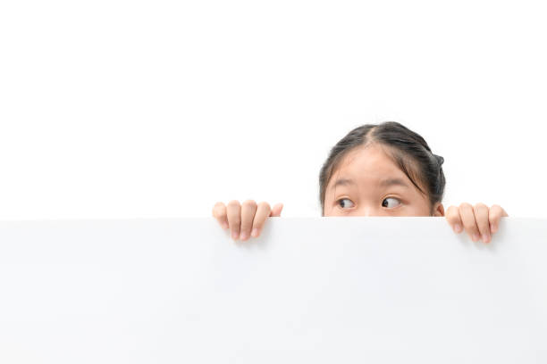 istock Young girl with beautiful eyes peeking over white corrugated plastic board, 1303323318