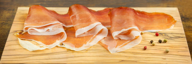 istock Rustic ham Slices of speck on wooden cutting board 1303323515