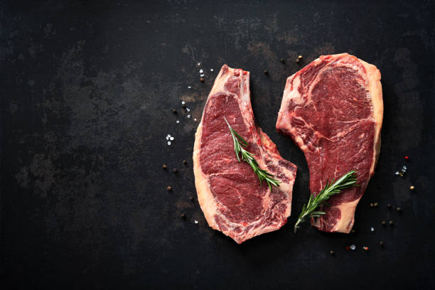 istock Two raw dry aged beef rib steaks (cote de boeuf)  with rosemary, pepper and salt 1303324740