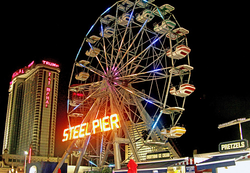 Atlantic City, New Jersey, USA - 19 July 2015: The Steel Pier ferris wheel on the Atlantic City boardwalk at night with hotels in the background at night.