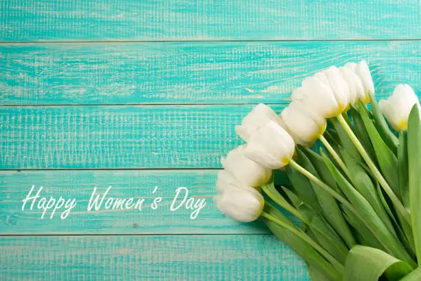 Womens day card. White tulips bouquet on wooden turquoise background