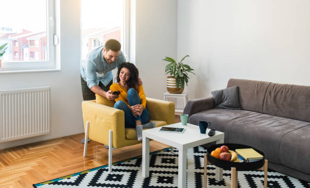 istock Happy couple using mobile phone together at home 1303326103