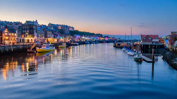 River Esk flowing through Whitby harbour in the evening showing reflections from the town