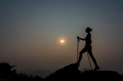 Silhouette Slim Girl of hikers walking in mountains. Woman hiker on a top peak  mountain. Life Balance Woman Exercise. Girl adventure fit trekking and happy activity freedom joy life concept.