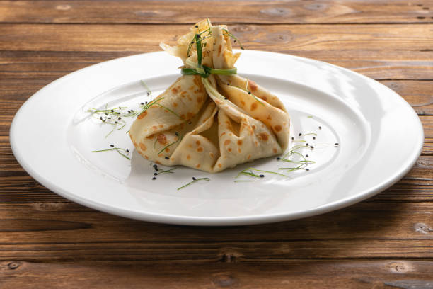 Vegetarian pancake with a filling in the form of a bag tied with green onions. Vegetarian pancake with vegetable filling in the form of a bag tied with green onions decorated with sprouted sesame seeds. Hot appetizer. apple cinnamon pancake stock pictures, royalty-free photos & images