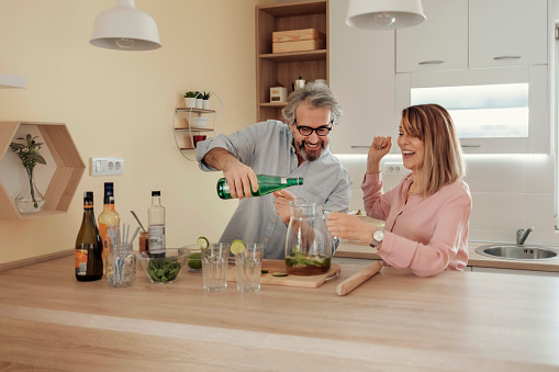 Husband and Wife Mixing Cocktail at Home, Enjoying Together