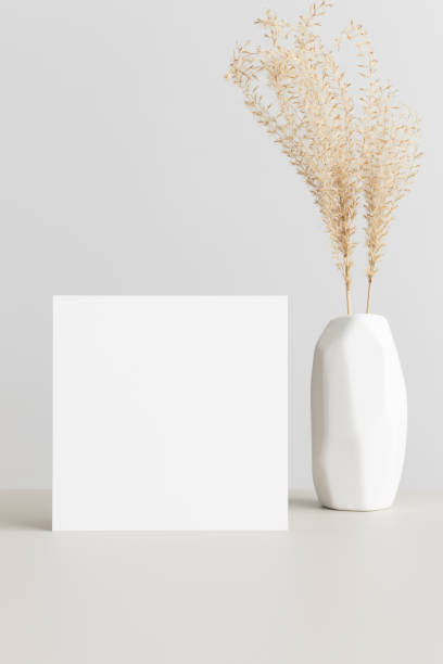 istock Square invitation card mockup with a dried grass on a beige table. 1303331443