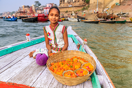 Little girl selling flower candles - a small candles inside a cup made from leaves and flowers. The Ganga is the most sacred river to Hindus.It is worshipped as the goddess Ganga in Hinduism.\nVaranasi is the spiritual capital of India and it is the holiest sacred citiy in Hinduism.