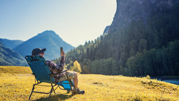 person, die mobiltelefon in freier wildbahn - campingstuhl stock-fotos und bilder