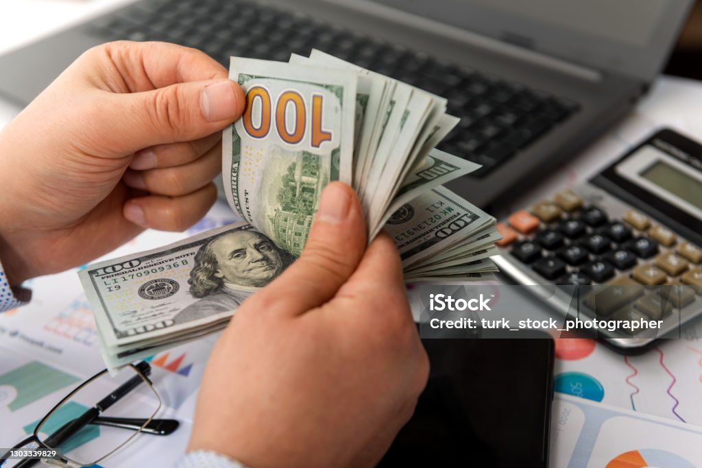 Businessman counting hundreds of dollars at his table Currency Stock Photo