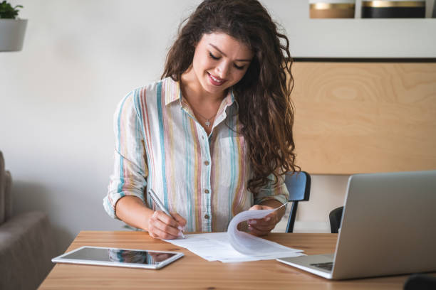 istock Smiling woman doing paper work at home 1303339965