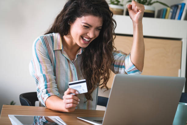 istock Excited woman cheering while using a laptop and credit card at home 1303340005