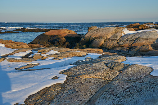 Sunset over the granite snow covered boulders on the coast of Maine