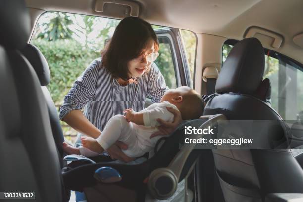 Asian Young Mother Putting Her Baby Son Into Car Seat Stock Photo - Download Image Now