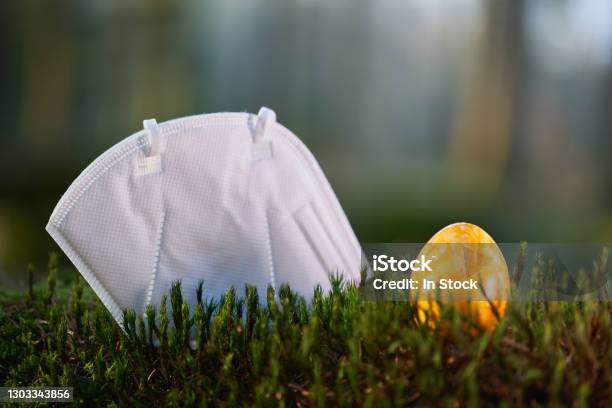 Fpp2 Face Mask On A Mossy Ground In The Forest Yellow Easter Egg Stock Photo - Download Image Now