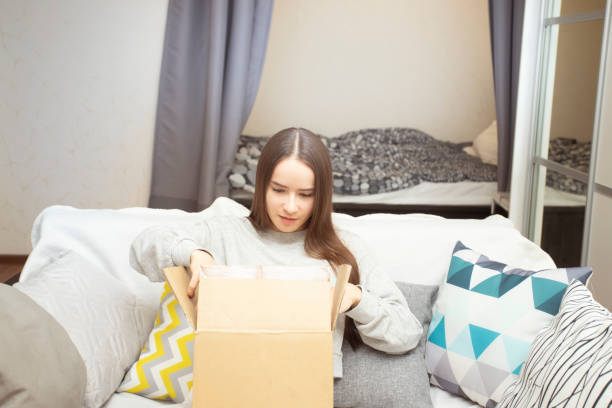 istock A young woman at home opens a mail parcel, is surprised 1303345189
