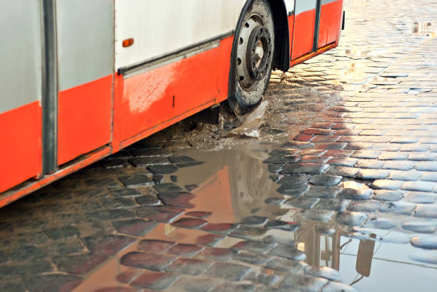 istock Water splashes from a car wheel. Dirty cobblestones with puddles. Early spring and snowfall. Blur as an artistic effect to convey movement. 1303345276
