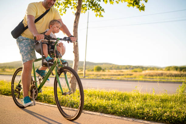 istock Father riding a bicycle with his son on a baby seat 1303345465