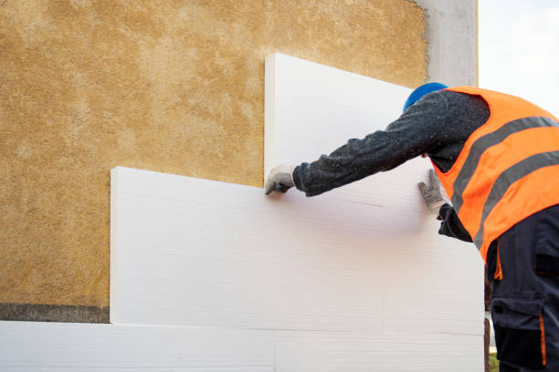 Construction worker placing styrofoam sheet insulation to the wall at construction site