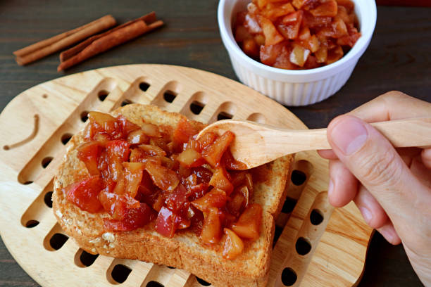 Hand topping a whole grain toast with delectable homemade apple cinnamon compote