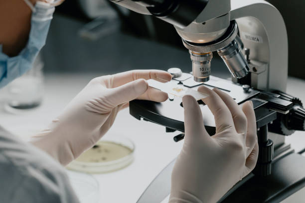 istock Anonymous Female Scientist Holding a Microscope Slide Wearing a Face Mask 1303348975