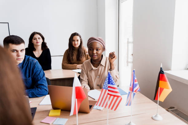 istock Foreign school private study with a school girl. Teacher explain grammar of native language using laptop. Prepearing to exam with tutor. English, British, German and Poland flags in front. 1303350649