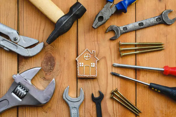 Many tools lie around a small house-shaped cookie. The concept of quality and construction or home renovation.