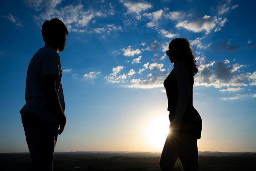 Young adults silhouettes on top of a mountain during sunset.