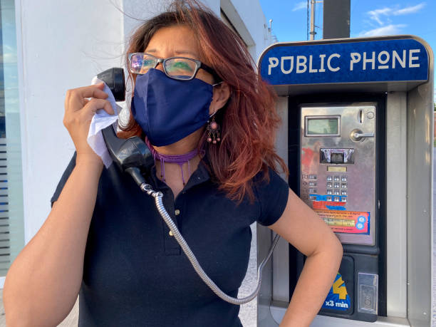 latina girl with mouth cover, using pay phone latina girl with mouth cover, using pay phone pay phone on the phone latin american and hispanic ethnicity talking stock pictures, royalty-free photos & images