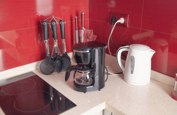 istock Set of cookware, white kettle and black coffee maker machine in kitchen. 1303358305