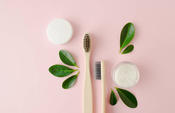 istock Eco-friendly bamboo toothbrushes, dentifrice and green leaf on pink background. 1303360761