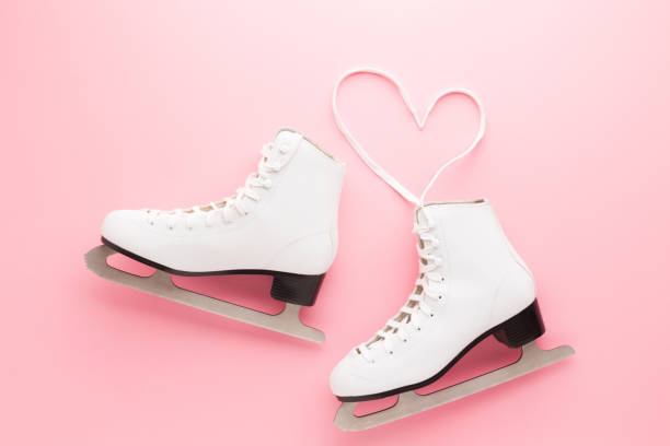 forma del cuore creata dai lacci delle scarpe. pattini da figura femminili bianchi su sfondo da tavolo rosa chiaro. colore pastello. primo piano. vista dall'alto verso il basso. - ice skates foto e immagini stock