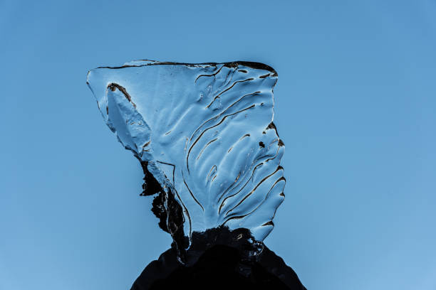 Organically shaped piece of ice against blue sky.