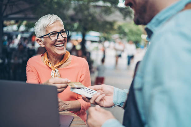 istock Smiling senior woman making a contactless payment 1303365619