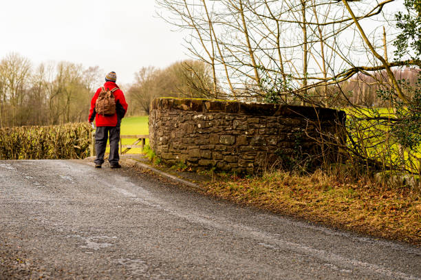 A senior man crossing an old road bridge in a rural setting
