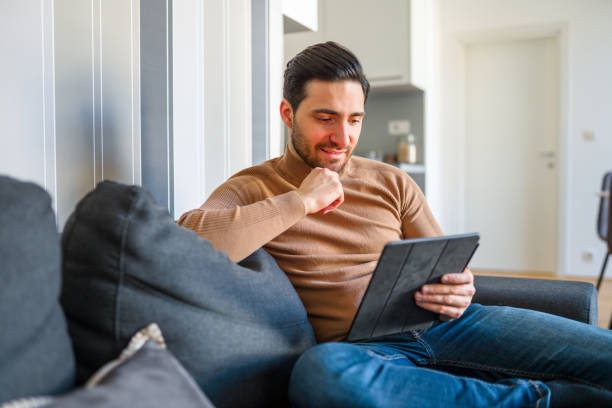 istock Caucasian Man Using Digital Tablet and Having Online Meeting on Sofa at Home 1303372525