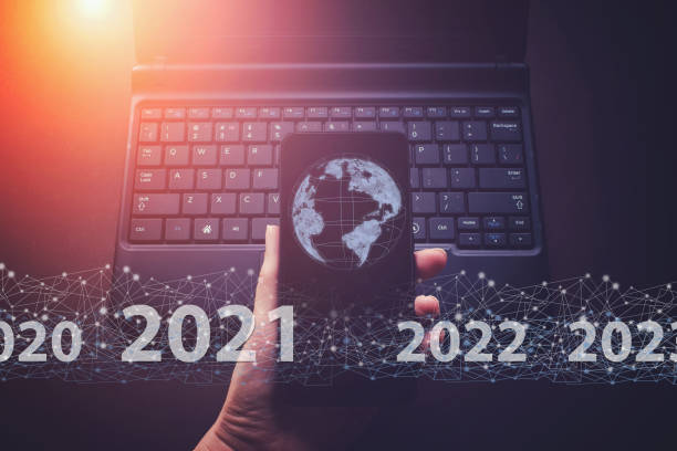 istock Showing virtual hologram globe, world 2021 on smartphone and keyboard laptop background. Concept for new year 2021. Protecting data personal information 1303373585