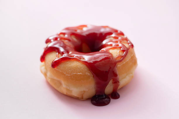 one donut with jam on pink background