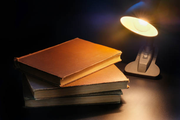 Magical book lying open on desk in library. Glowing pages illuminates surrounding.
