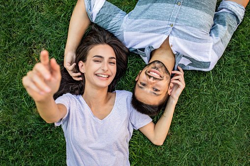 Portrait of young man and woman lying on the grass and smiling