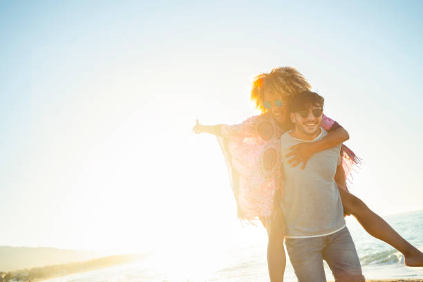 istock Couple playing piggyback on the beach at sunset or sunrise. 1303375231