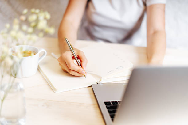 istock Woman writes in notebook on desk with laptop 1303377201