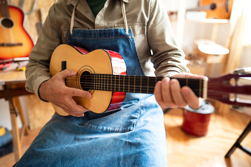Closeup view on acoustic guitar in hands of unrecognizable craftsman.