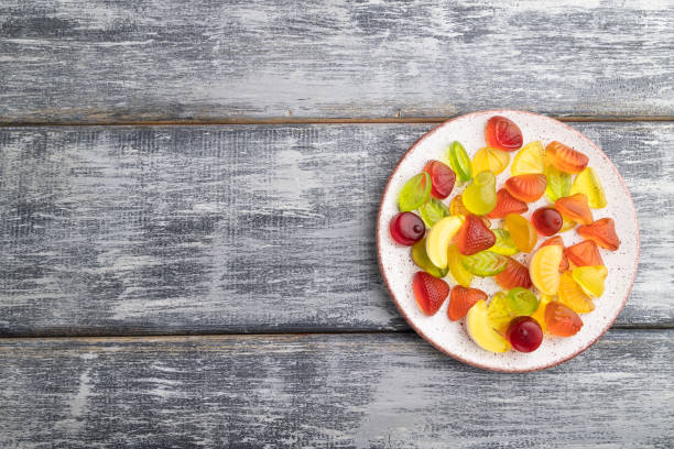 istock Various fruit jelly candies on plate on gray wooden background. top view, flat lay, copy space. 1303379401