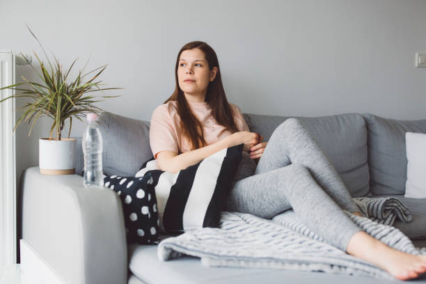 istock Woman resting on the sofa, focus on water bottle next to her 1303380503