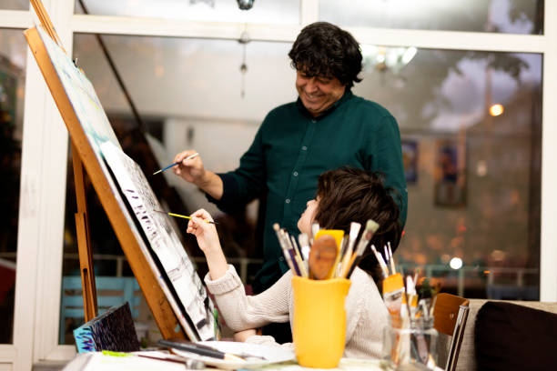 istock Father is encouraging her son while he is painting 1303383374