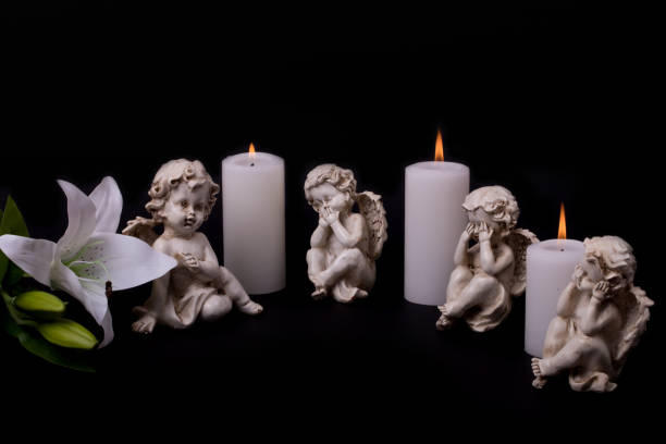 istock Angels with candles and white lily flower on a black background 1303383509